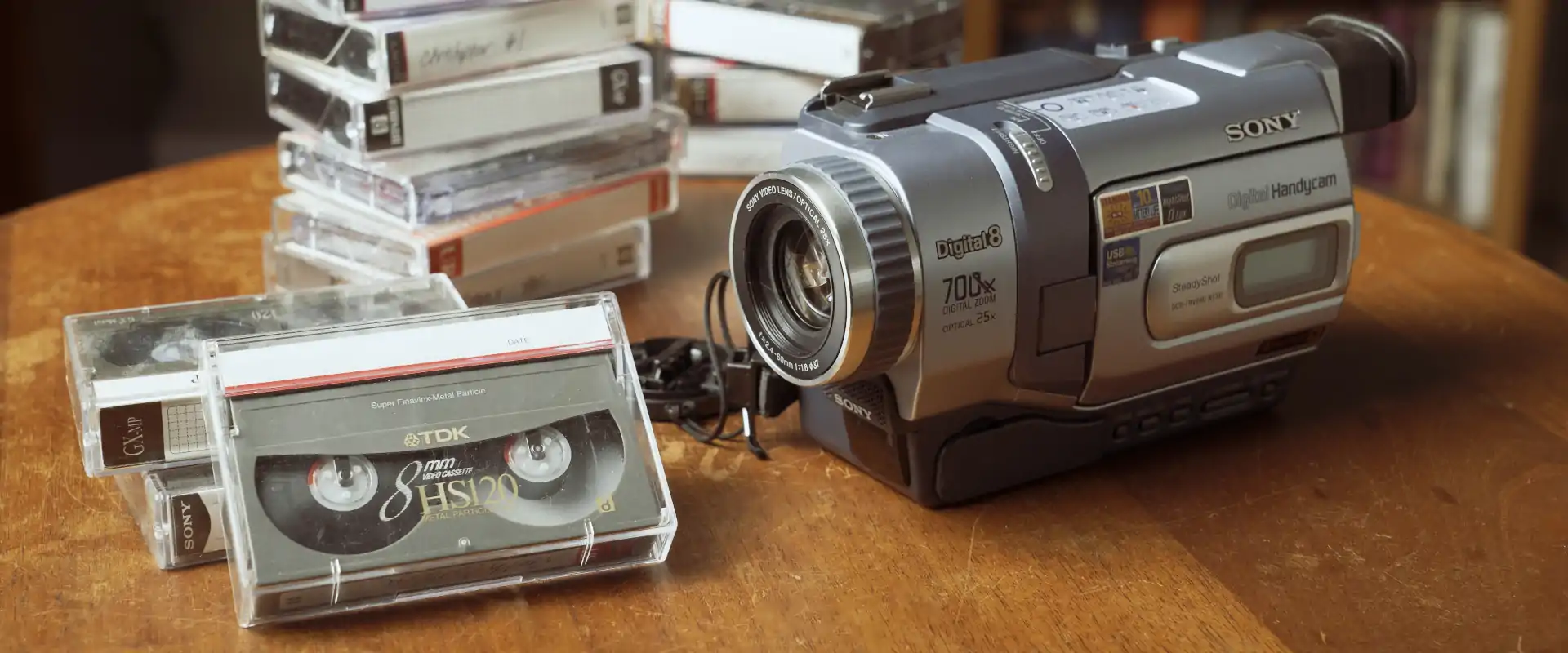 Sony Digital8 Handycam met 8mm Digital8-videobanden Sony Digital8 Handycam videocamera op houten tafel naast meerdere 8mm Digital8-videobanden, klaar voor digitalisering naar modern formaat zoals MP4